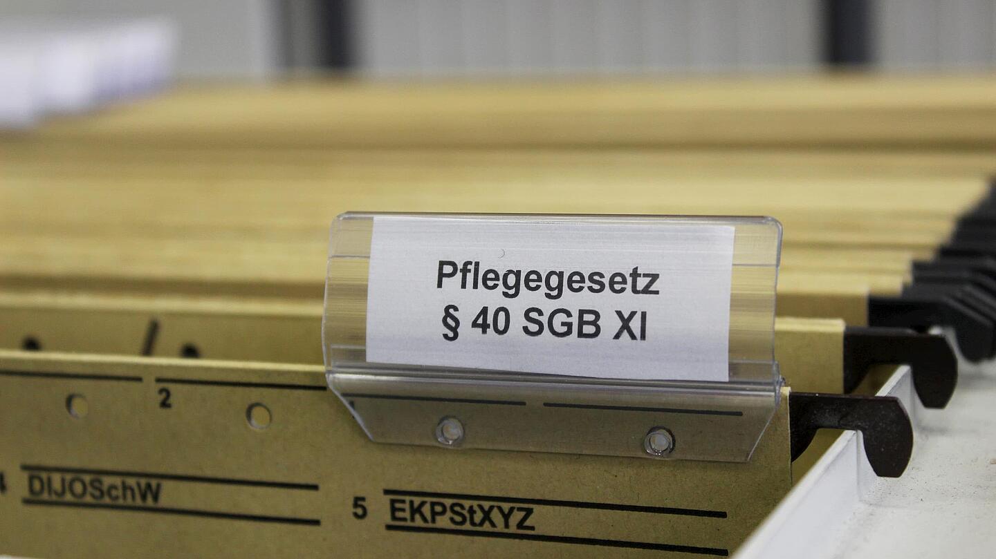 Pflegegesetz-Aktenordner Halterung mit Aktenordnern, bei dem einer mit dem Pflegegesetz beschriftet ist