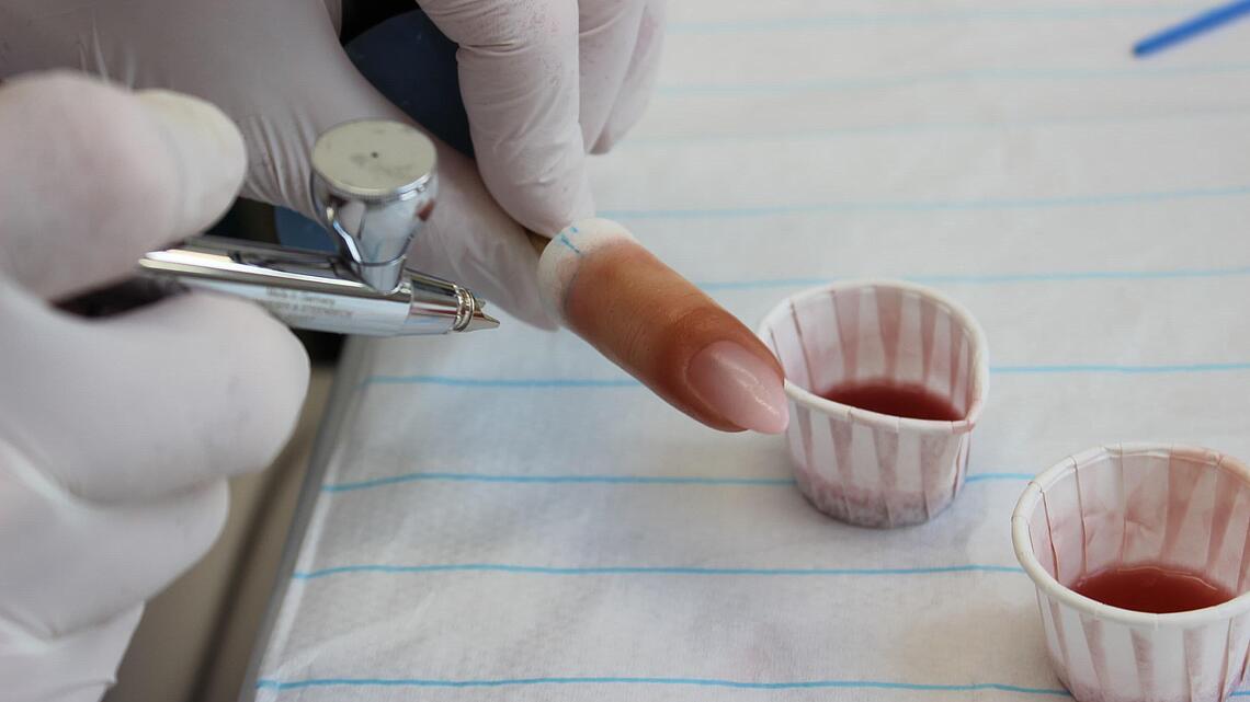 Airbrush-Arbeiten an Fingerprothese Airbrush-Pistole mit entsprechenden Farbtöpfchen zur Färbung einer Fingerprothese