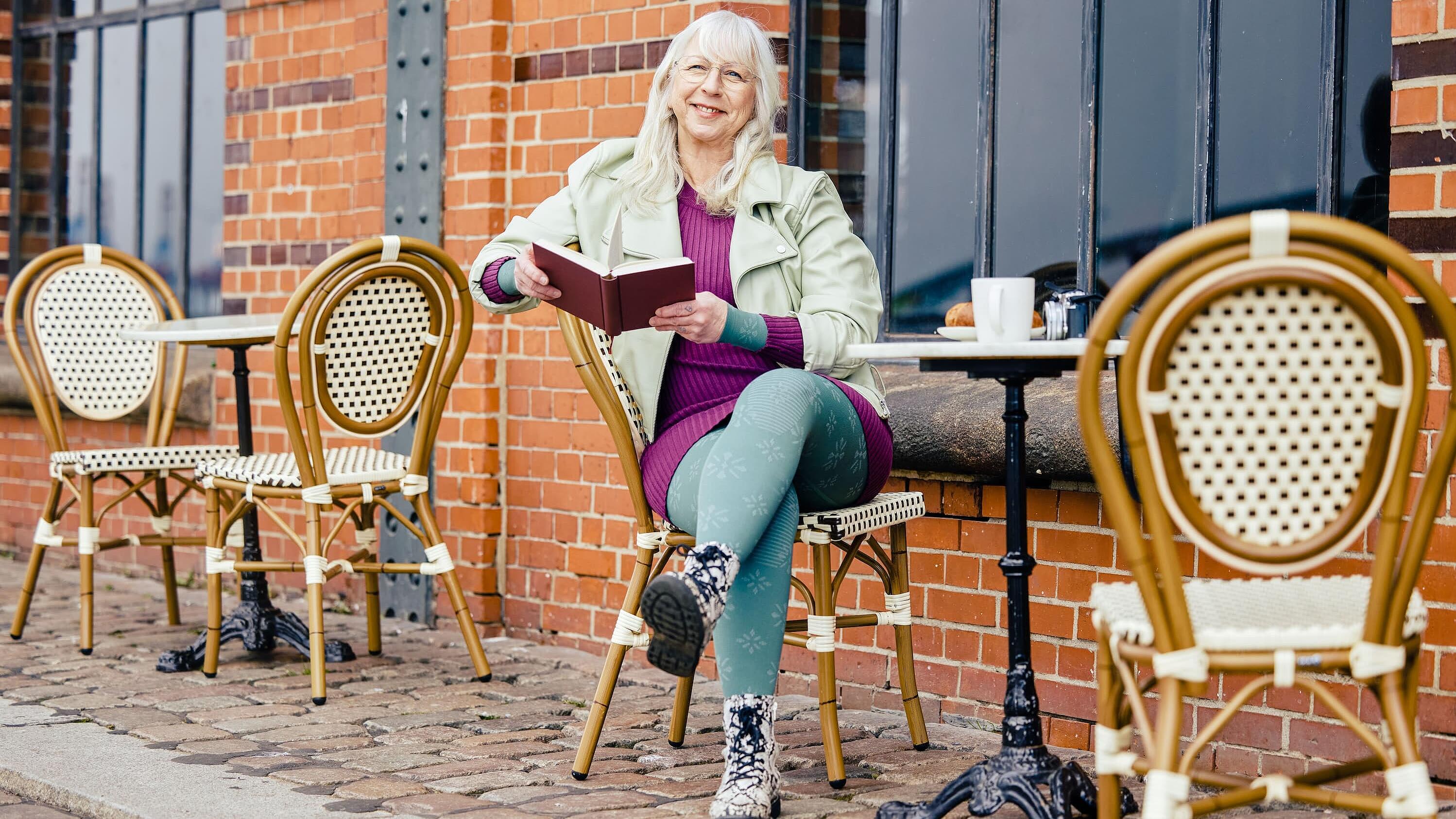 Lymphcafé, Bildquelle: medi Frau mit Kompressionsstrumpfhosen sitzt mit einem Buch vor einem Café, Bildquelle: medi