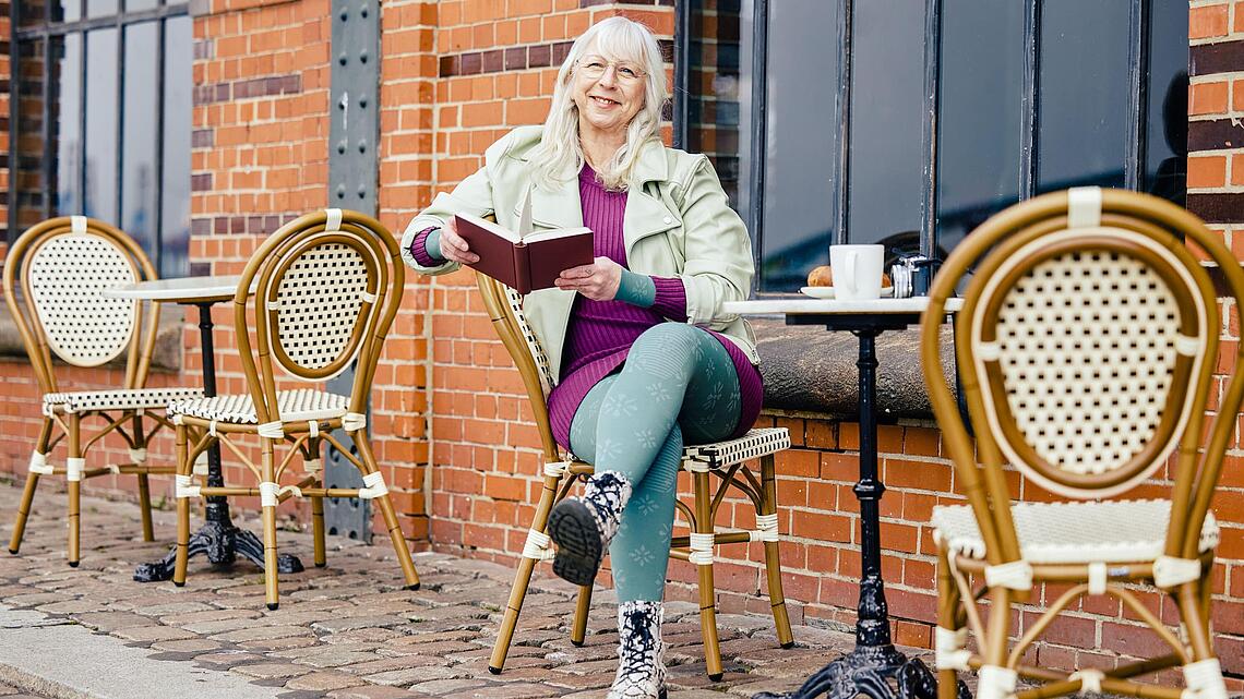 Lymphcafé, Bildquelle: medi Frau mit Kompressionsstrumpfhosen sitzt mit einem Buch vor einem Café, Bildquelle: medi