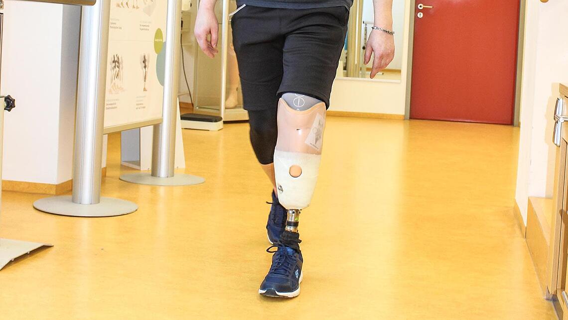 Mann läuft mit linker Beinprothese durch Flur bei Prothesen-Gebrauchsschulung Mann läuft mit Beinprothese bei Prothesen-Gebrauchsschulung