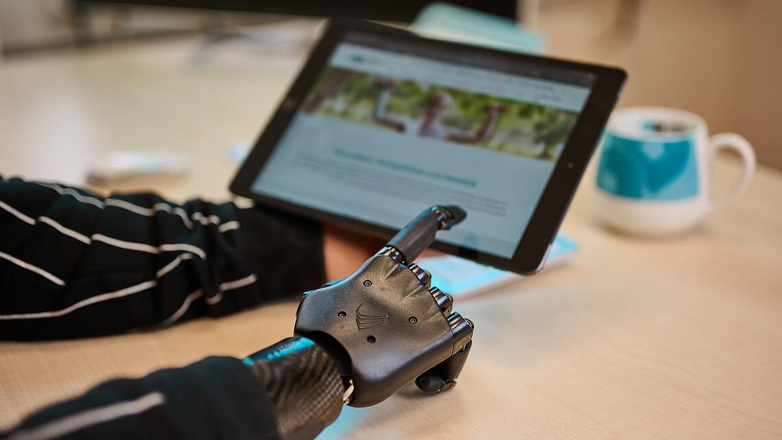 myoelektrische Armprothese mit Tablet, Quelle: newpic photography schwarze myoelektrische Armprothese zeigt auf Tablet, Quelle: newpic photography