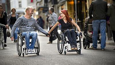 glückliches Paar aus Mann und Frau, die händehaltend im Rollstuhl sitzen, ©Invacare