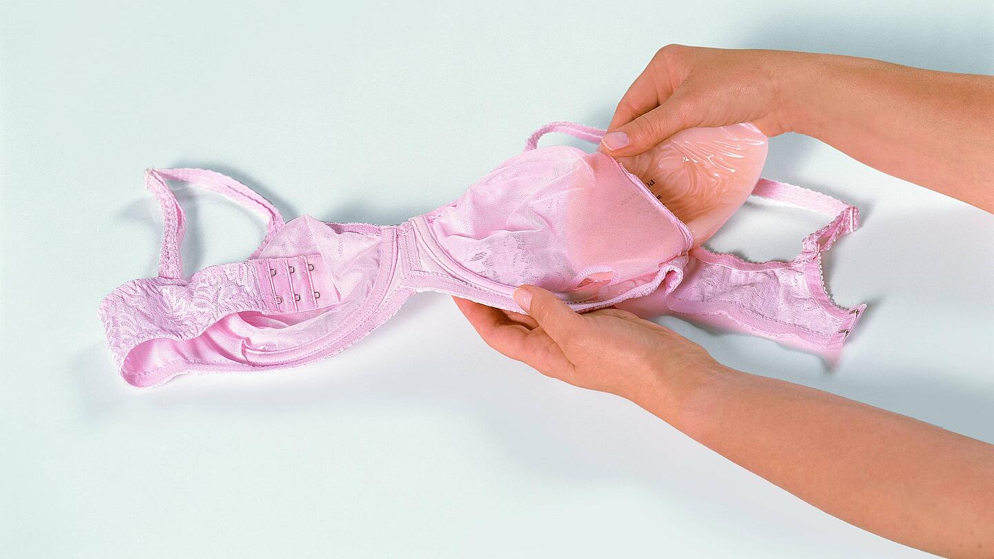 BH mit Epithese | Copyright: Amoena Medizin-Orthopaedie-Technik GmbH Hand schiebt Epithese in BH | Copyright: Amoena Medizin-Orthopaedie-Technik GmbH