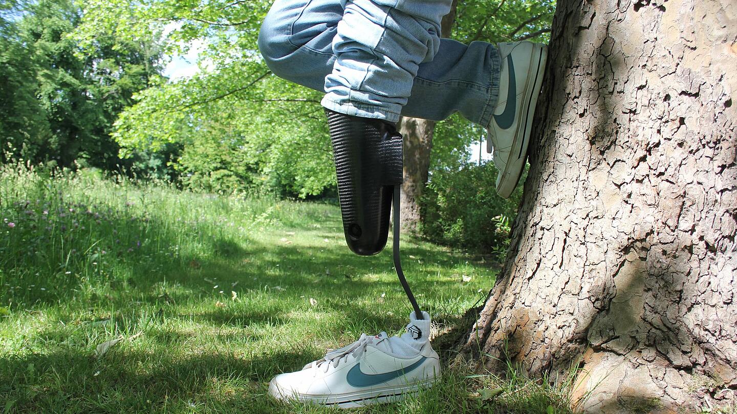 hochaktive Alltagsprothese mit Cheetah-Prothesenfuß am Baum gelehnt Träger einer Unterschenkel-Sportprothese mit Cheetah-Prothesenfuß lehnt am Baum
