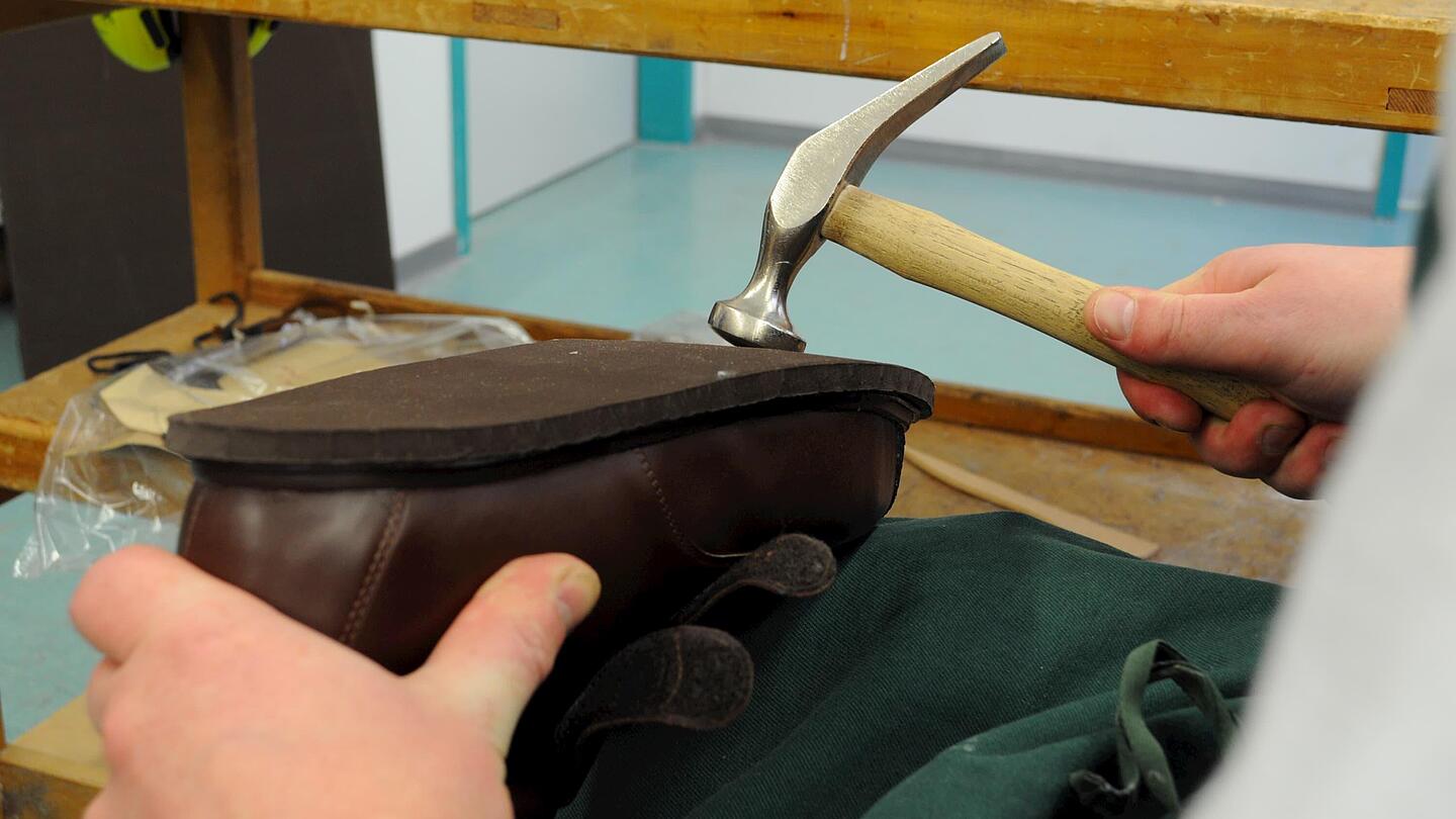 Annageln der Sohle mit dem Hammer die Sohle des Schuhs wird zur Befestigung mit dem Hammer bearbeitet