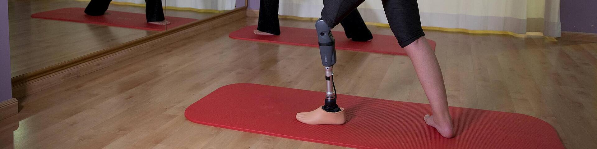 Frau beim Yoga mit Unterschenkelprothese Rheo Knee, © Copyrights by Össur hf. Frau beim Yoga vor dem Spiegel mit Unterschenkelprothese Rheo Knee, © Copyrights by Össur hf.