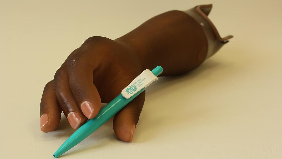 dunkelhäutige myoelektrische Armprothese dunkelhäutige myoelektrische Armprothese mit Kugelschreiber