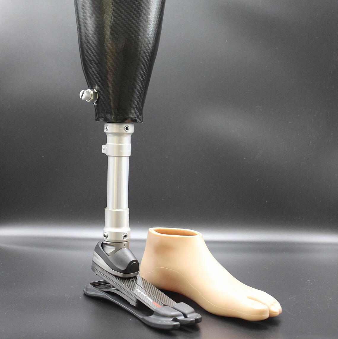 Unterschenkelprothese mit Spezialfuß für unebene Untergründe Unterschenkelprothese mit Spezialfuß für unebene Untergründe, daneben steht der kosmetische Überzug