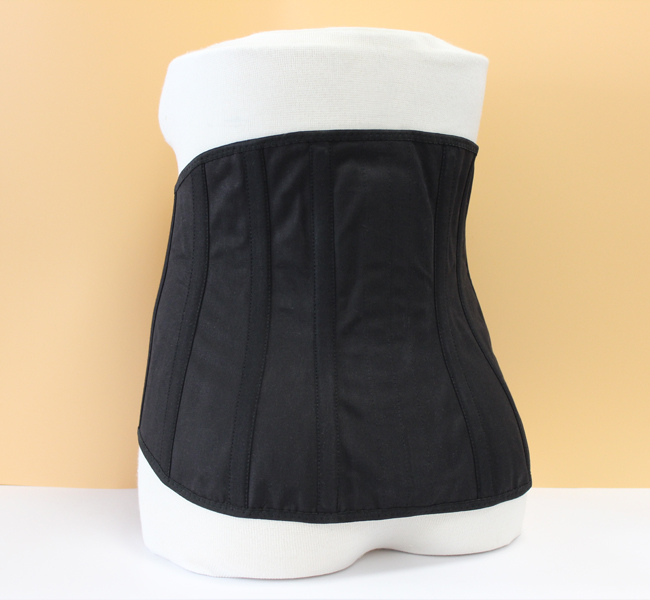 Rückenansicht eines Kreuzstützmieders Rückenansicht eines schwarzen Kreuzstützmieders mit Klettverschluss zur Stabilisierung und Haltungsverbesserung durch zirkuläre Kompression